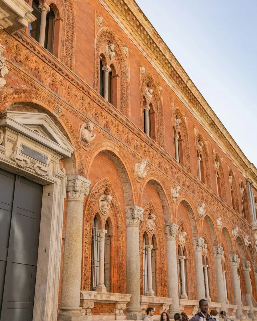 Milano’da tarihî tuğla cepheli bir üniversite binasının önündeki insanlar
