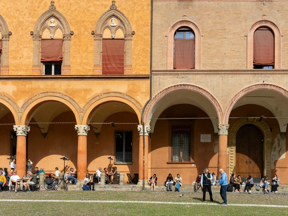 Bologna’da tarihî revakların önündeki çimenlikte oturan gençler