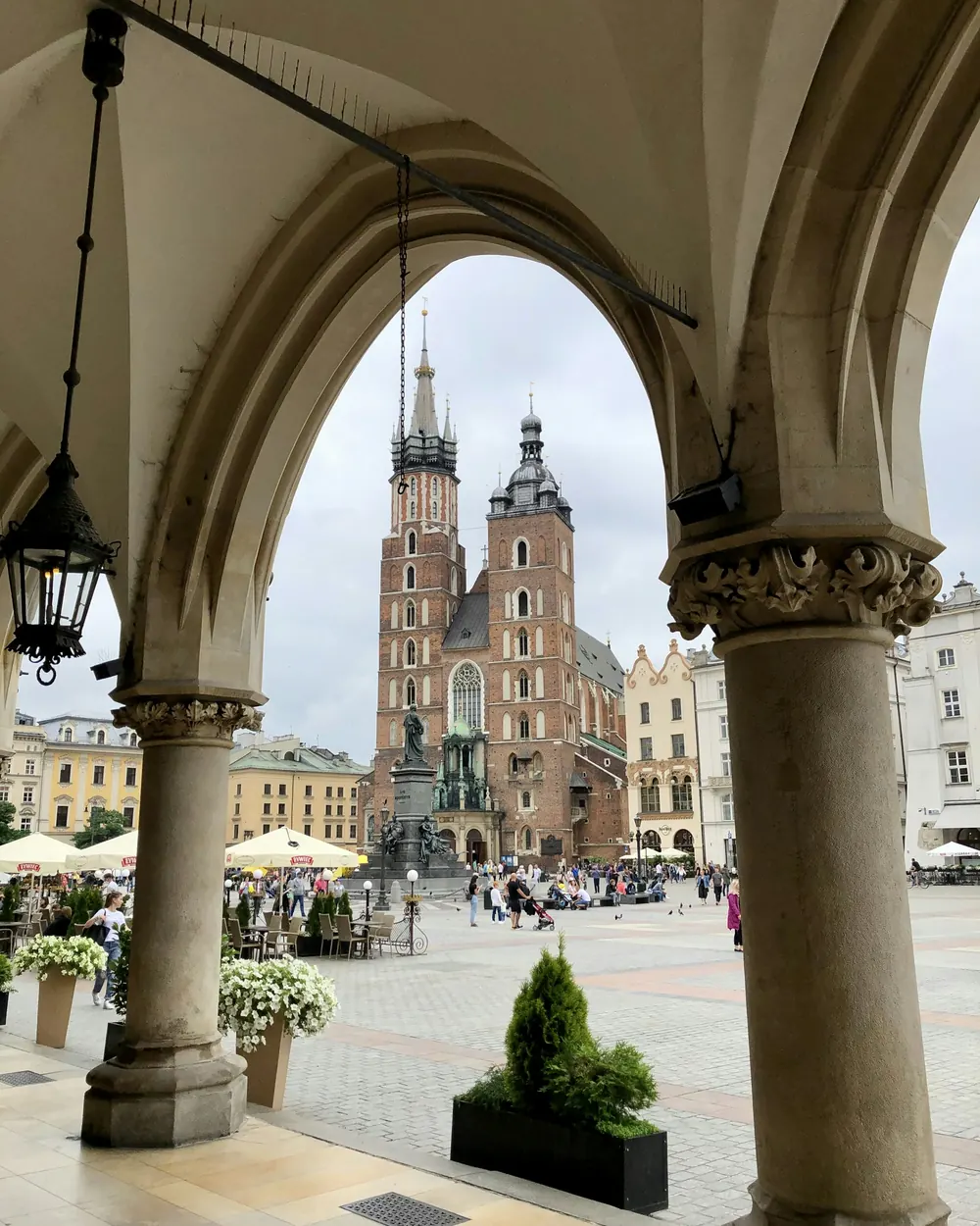 Kraków'da Sukiennice revaklarının kemerinden görünen Mariacki Bazilikası ve meydan