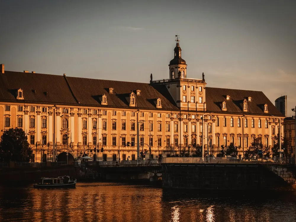 Akşam ışığında nehir kıyısındaki Wrocław Üniversitesi binası